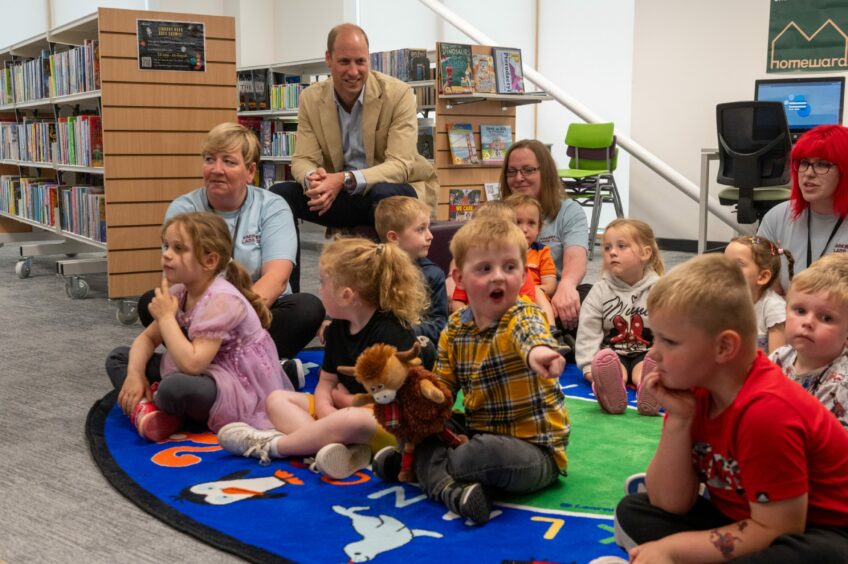 Prince William and children sitting on floor.