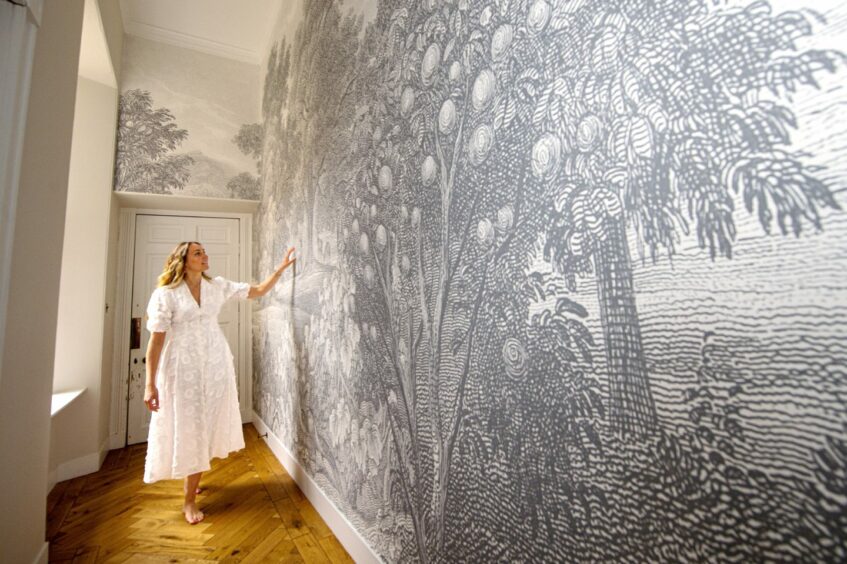 Christina Horspool admiring the black and white forest-print wallpaper