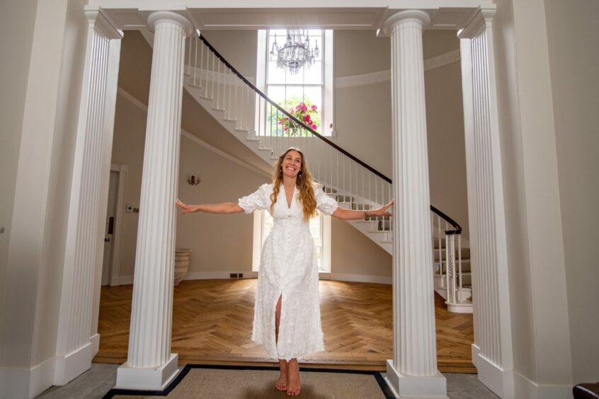 Christina Horspool standing in the entrance of the house, standing between two white pillars
