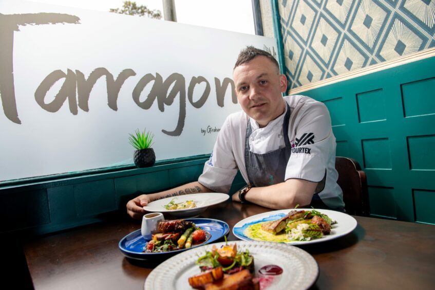 Graham Mitchell sitting inside Tarragonwith four dishes on the table in front of him