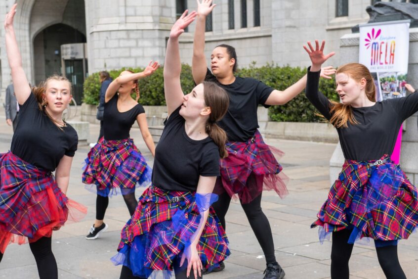 Dancers from Citymoves performing outside Marischal Square wearing tartan skirts 