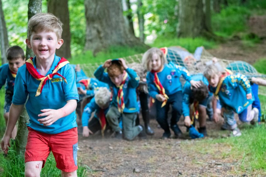 A young boy in his Beavers uniform running ahead of the obstacle course group