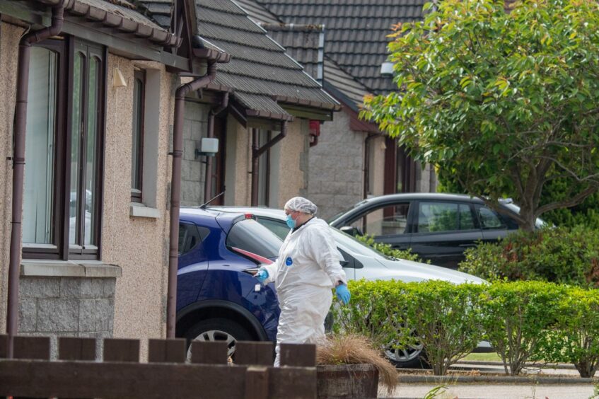 A forensics officer in a white suit approaching the Leslie Crescent house 