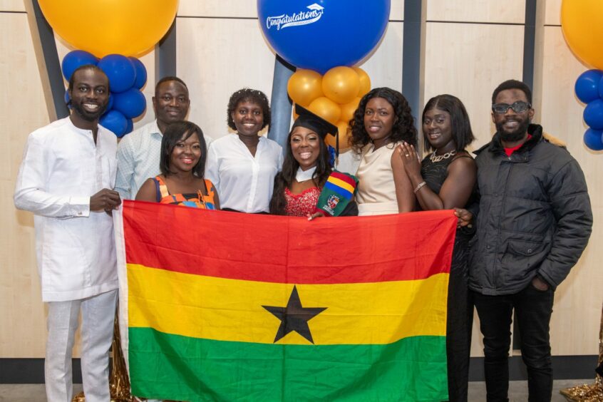 Rhoda Donkor of Ghana with her family, holding a Ghanaian flag.