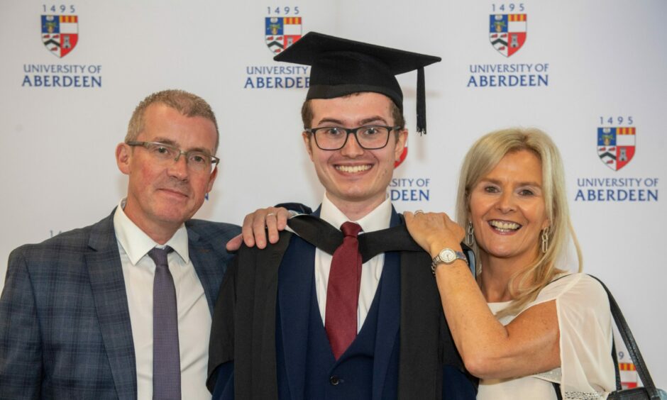 Aberdeen University student smiles for graduation pictures with his parents.