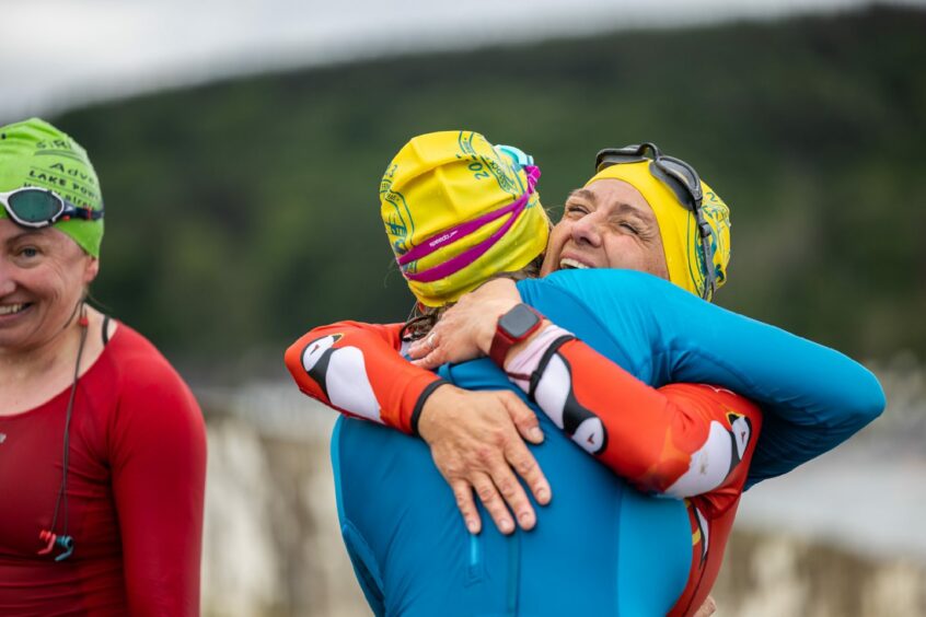 Two swimmers hug after crossing the Moray Firth.