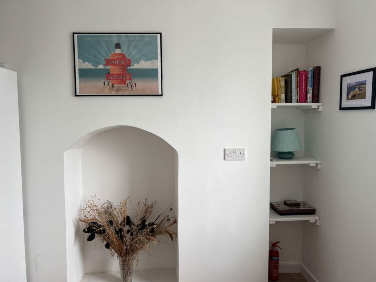 A blue and red Whisky Galore print on the wall inside the home 