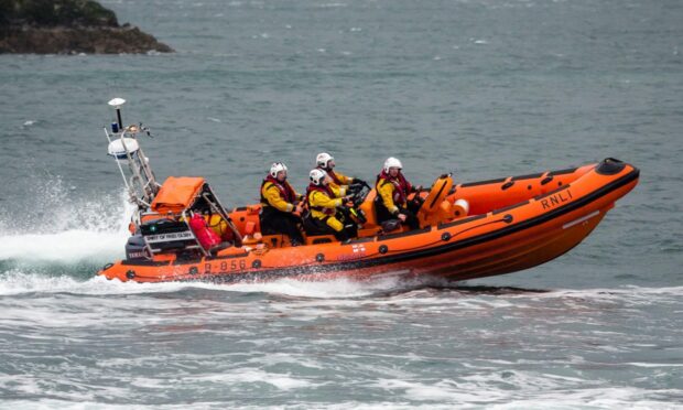 Side-on view of Kyle RNLI lifeboat at speed in water with crew on board.