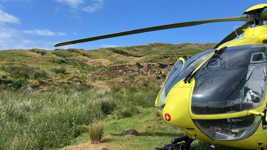 Tourist rescued from Isle of Luing hillside with SCAA helicopter in forefront 