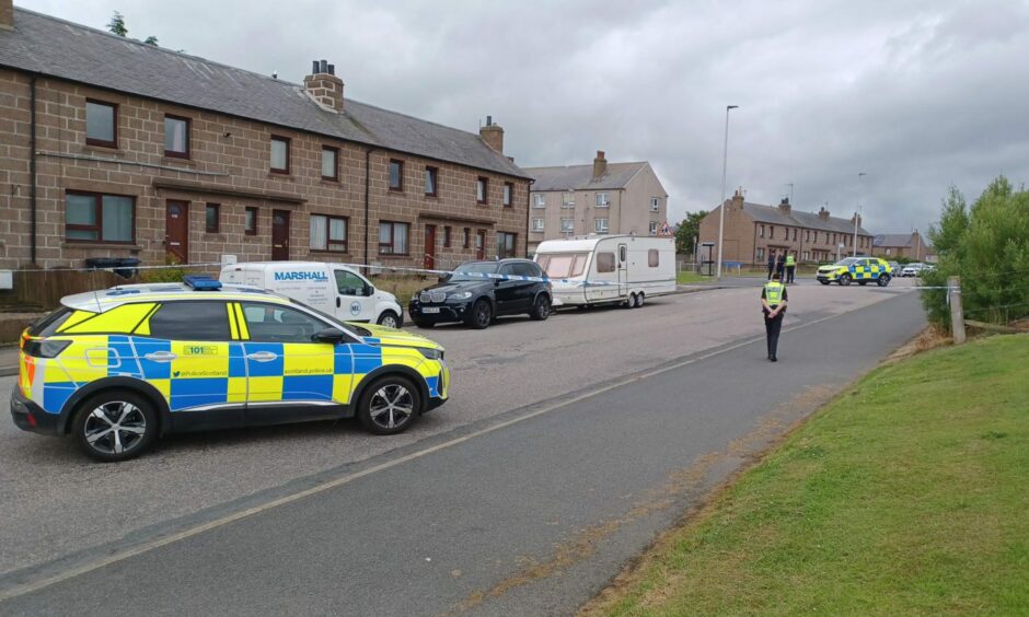 Police car parked across the street and officers standing outside on Catto Drive in Peterhead.