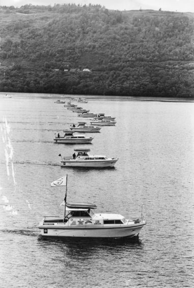 A view of small cruisers spread in a line across Loch Ness with hills in the background