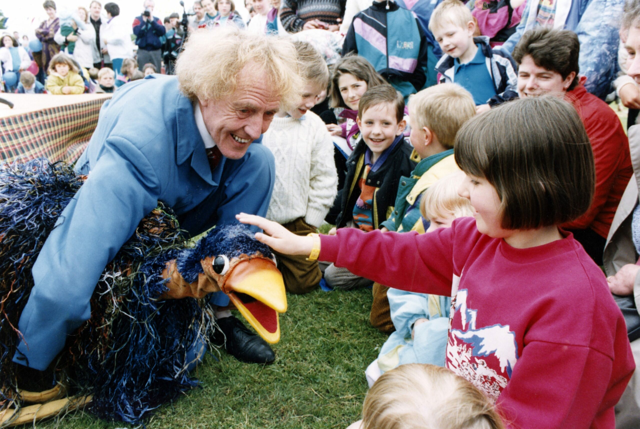 Rod Hull holding the puppet Emu while a young girl pats it's head