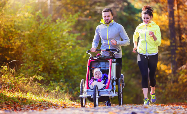 Couple jogging with their toddler in a pram at Aden Meadows.