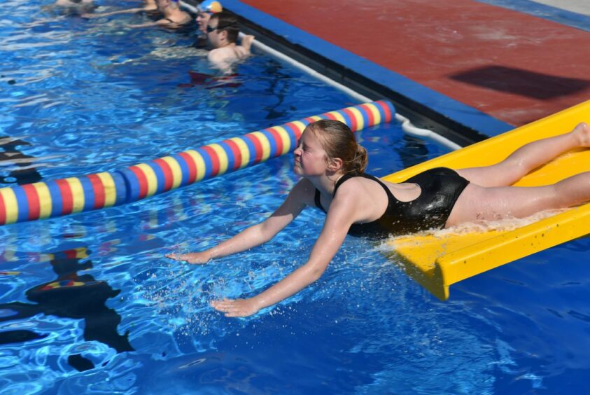 Girl going down the slide into the pool.