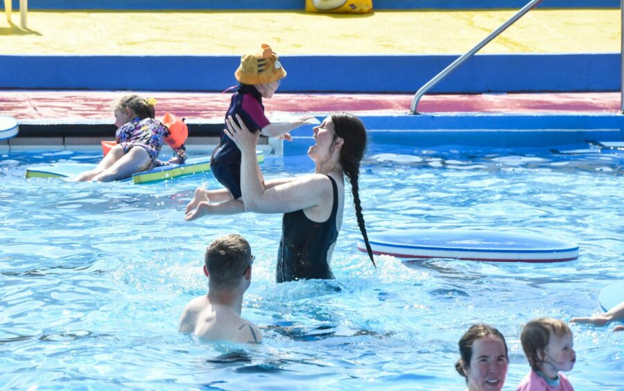 Woman holds young girl in the air.