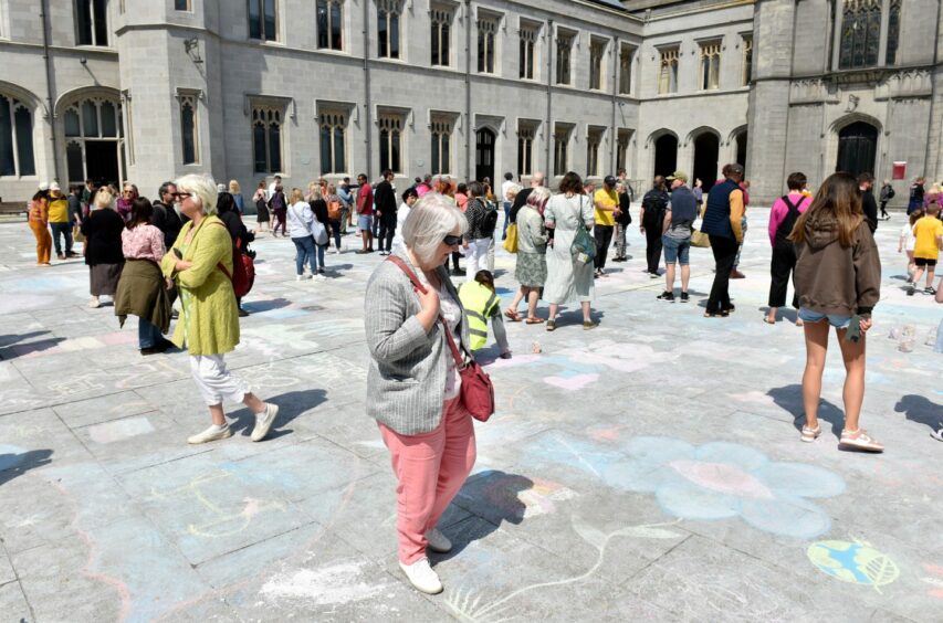 Public walk round admiring chalk artworks. 
