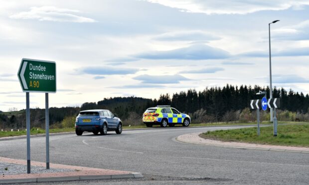 A police car watching traffic on the Cleanhill roundabout on the AWPR, as a car drives round.