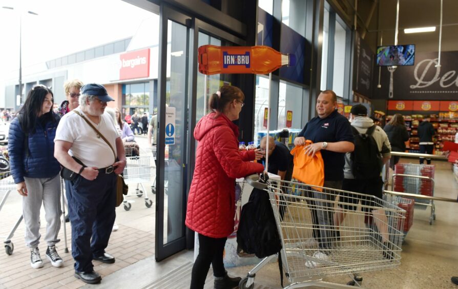 Customers receiving a goodie bag from Irn Bru as they arrive.