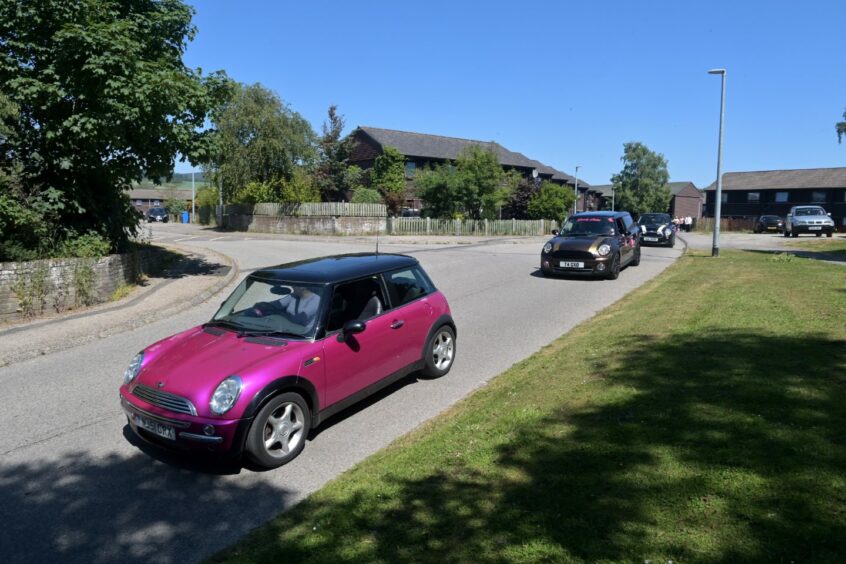 The procession of Minis, including Mia's favourite pink Mini, in Milnafua. Image by Sandy McCook / DC Thomson.