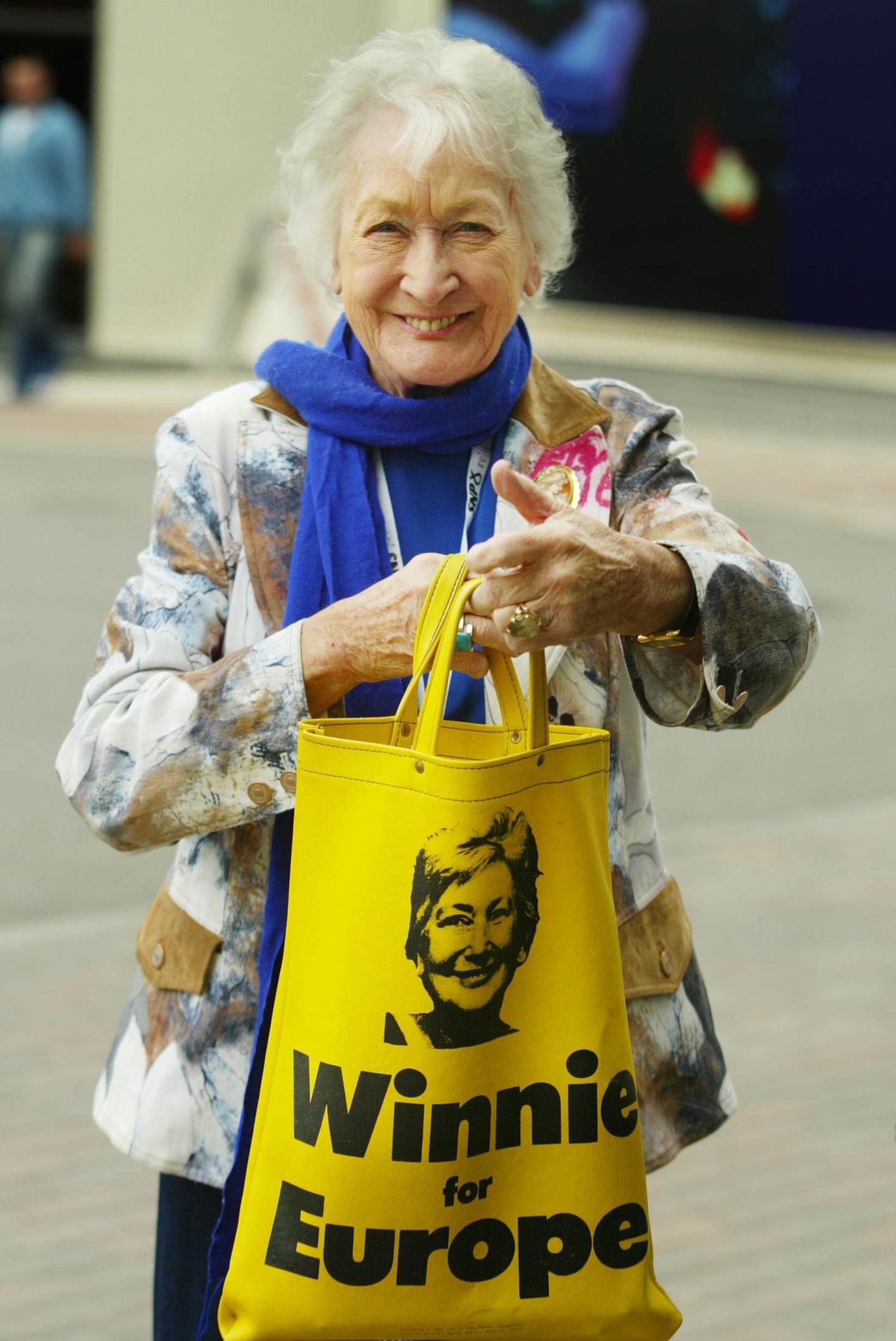 Winnie Ewing holding up a yellow "winnie for europe" tote bag