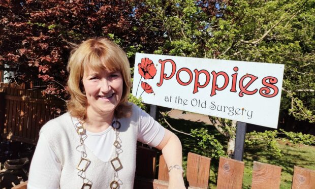 Laurencekirk Poppies nursery manager smiling in front of the Poppies sign