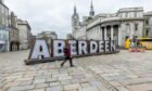 Giant Aberdeen letters with someone walking past.