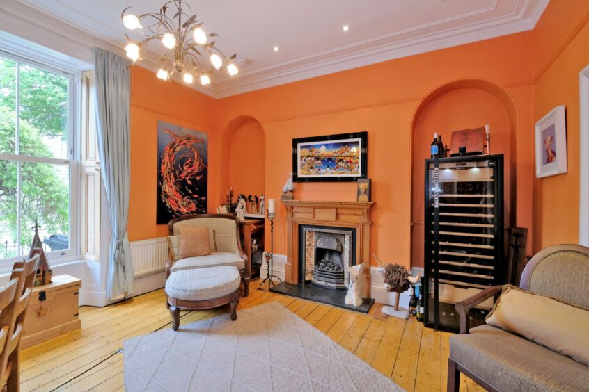 Living room inside the Aberdeen west end home with tangerine walls and earth-tone furniture.