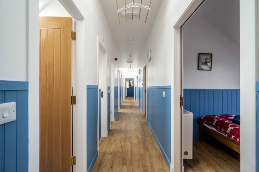 A bright blue long corridor in Stoer Hostel in the Sutherland Highlands on the NC500. 
