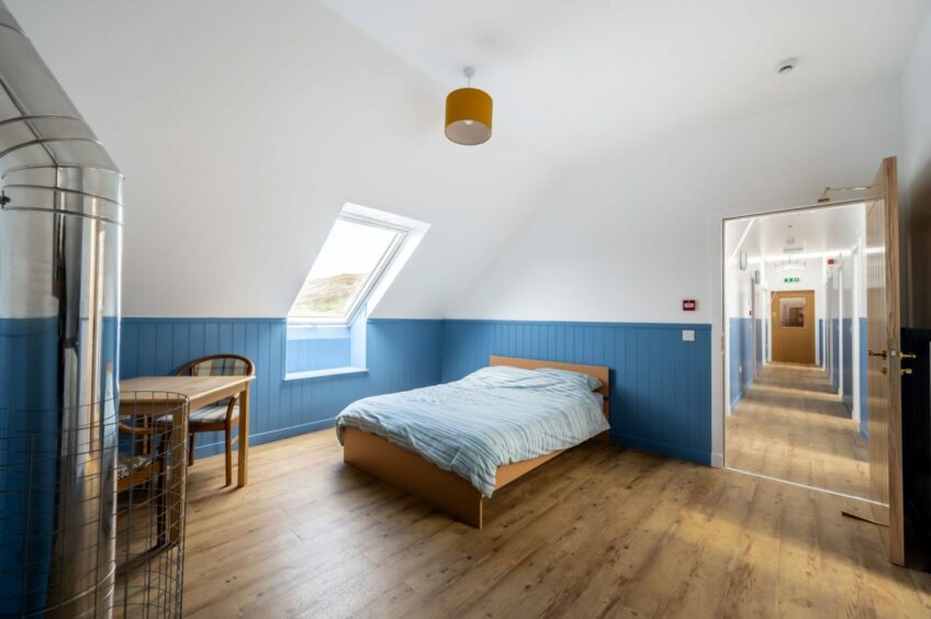 A bright blue bedroom with a view of a long corridor in Stoer Hostel in the Sutherland Highlands on the NC500. 