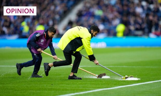 Security stewards and ball boys helped ground staff clear the waterlogged pitch at Hampden Park at the beginning of Scotland's men's team's recent game against Georgia (Image: Stuart Wallace/Shutterstock)