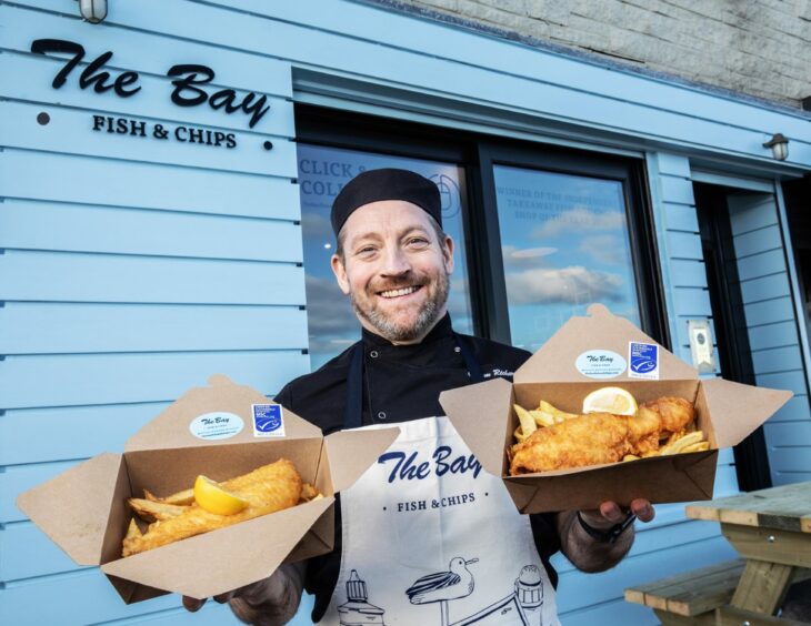 The Bay chef holding fish and chips dish.