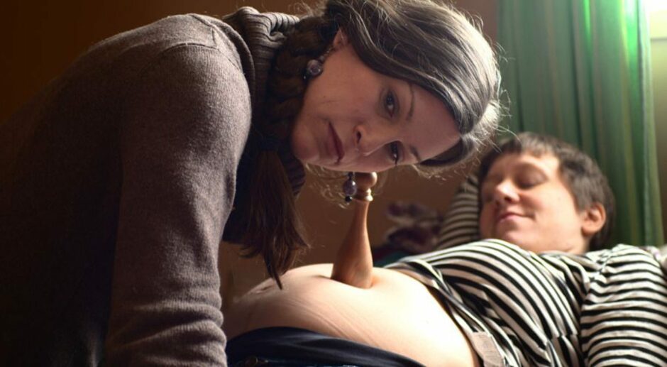 A frame from a film shown at SQIFF, with a person listening to a pregnant person's stomach.