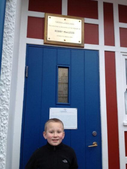 Young Bobby stands outside his great-great grandfather's memorial plaque at RNLI Tobermory.