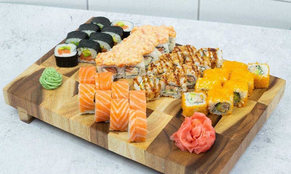 A selection of sushi along with some Kimchi and wasabi on a serving board
