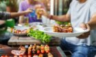 A man with a barbecue plate at a party between friends