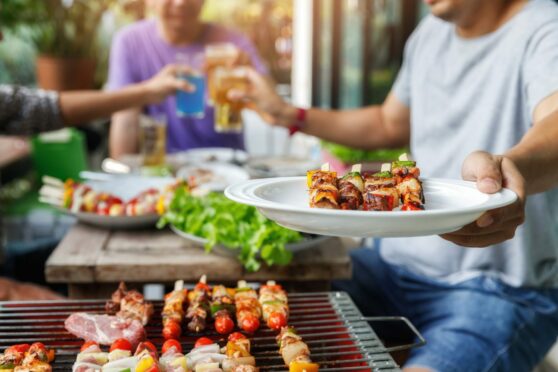 A man with a barbecue plate at a party between friends