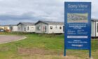Sign showing Spey View with holiday homes behind it.