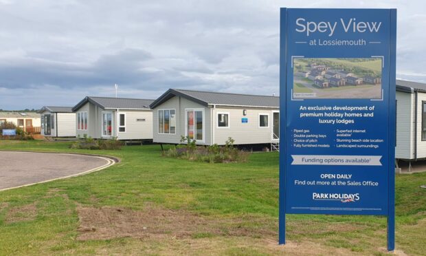 Sign showing Spey View with holiday homes behind it.