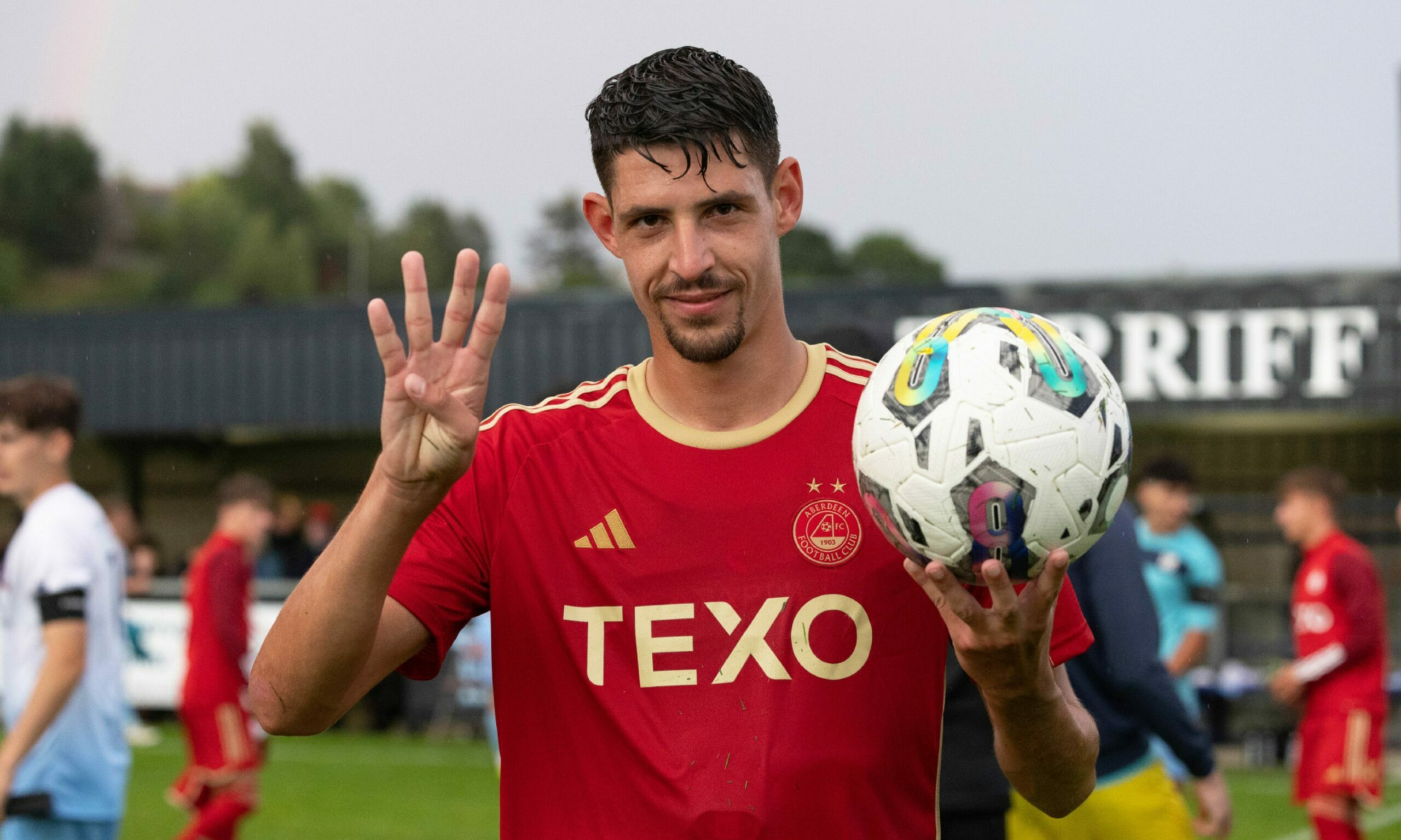 Aberdeen's Ester Sokler holding a football in one hand and holding up four fingers with the other