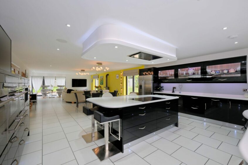 The modern open plan kitchen and living room with tiled floors and a kitchen island