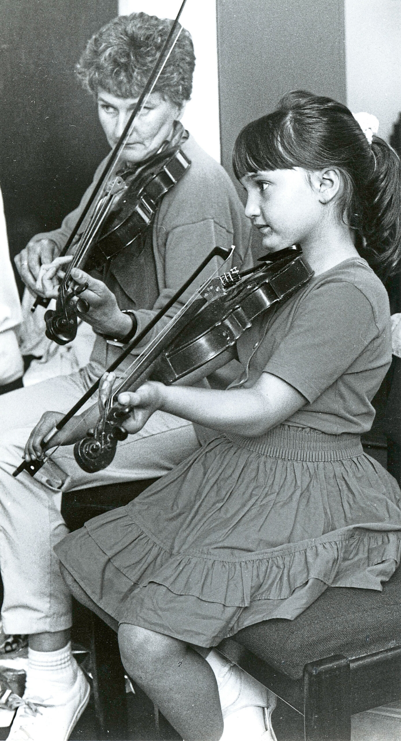 A woman and girl playing violin together