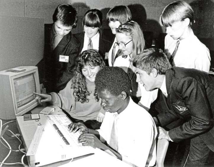 A group of St Machar Academy students and their teacher gathered around a word processor.
