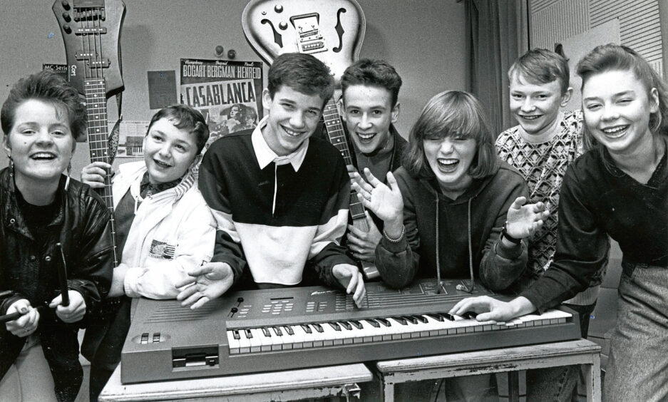 Members of the group False Alarm surrounding a keyboard with some of their instruments
