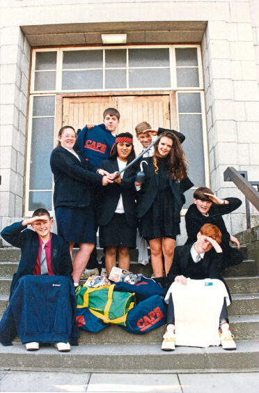 Pupils on a staircase saluting to the camera, one of them is holding a toy sword and wearing a headband and eye patch