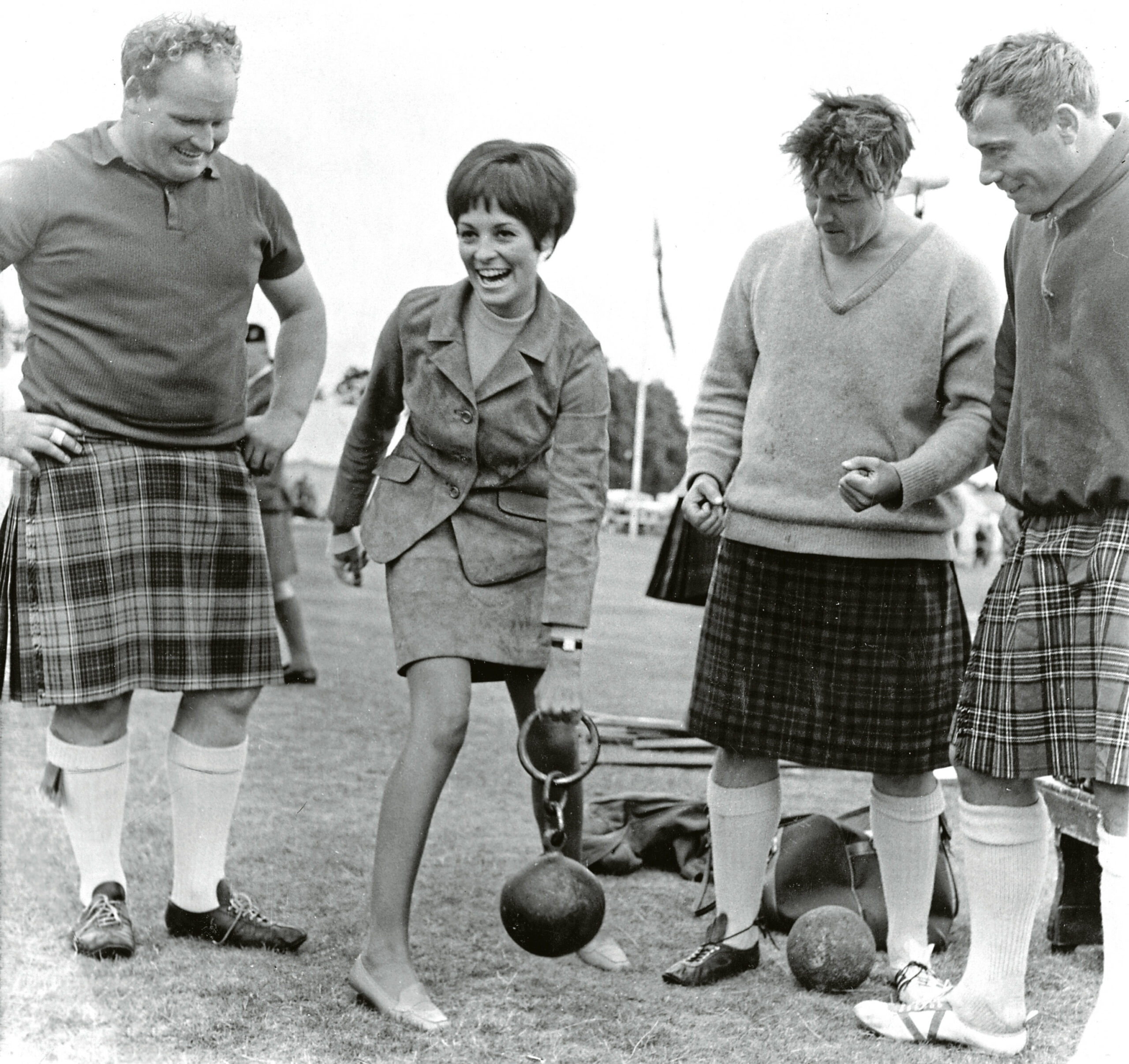 Miss Great Britain 1967 Jennifer Gurley tries to lift the 58lb weight, watched by Bill Anderson, Charlie Allan and Arthur Bowe.