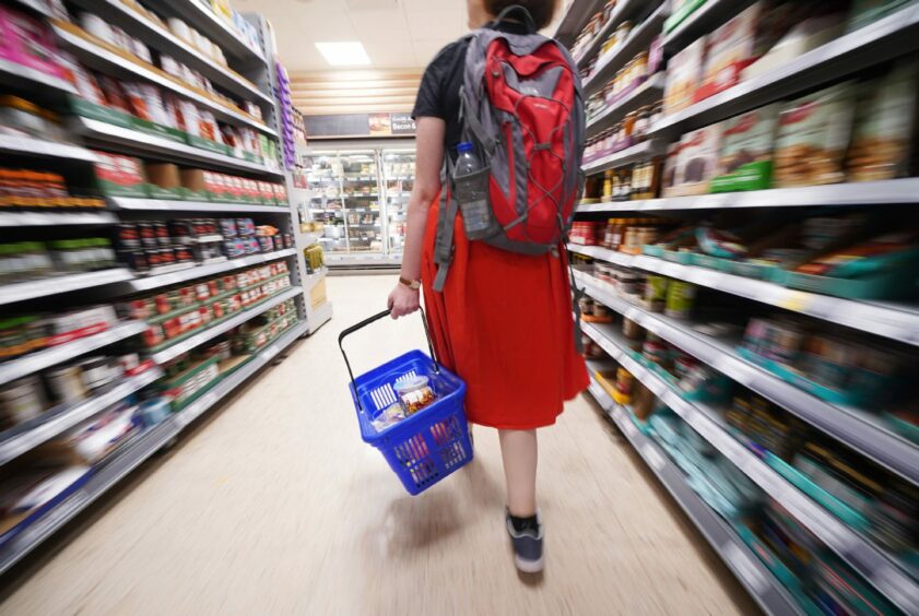 Shopper walking through the aisle of a Tesco supermarket.