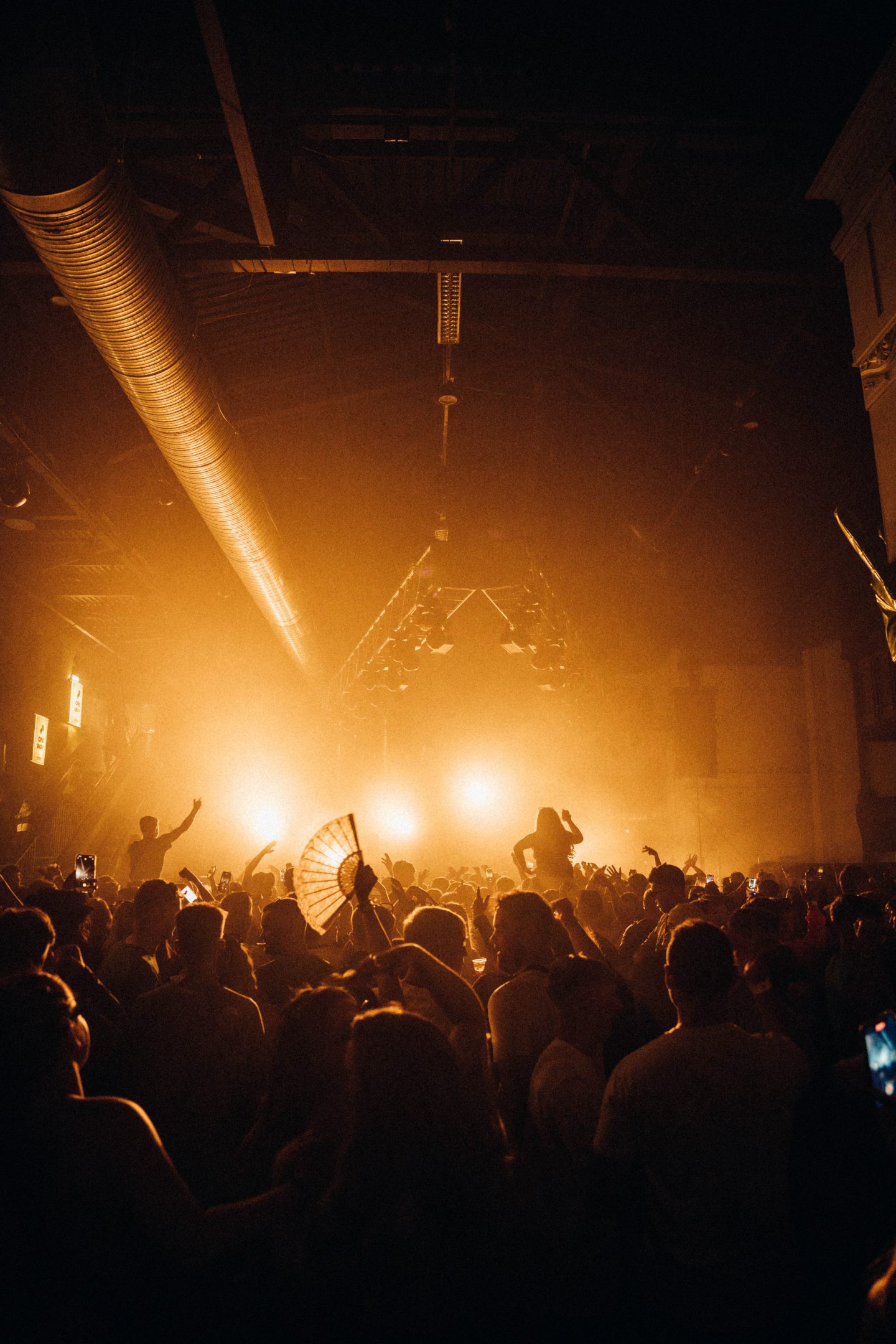 Crowds dancing under a yellow/orange light