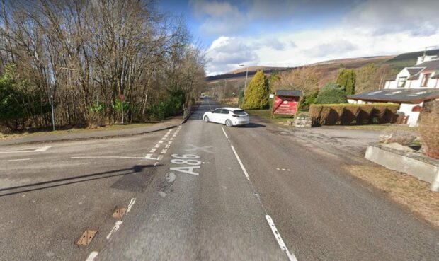 A86 road with a car driving on it, with trees and hills in the background.