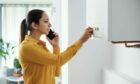 Worried woman calling a boiler breakdown emergency service using her smartphone