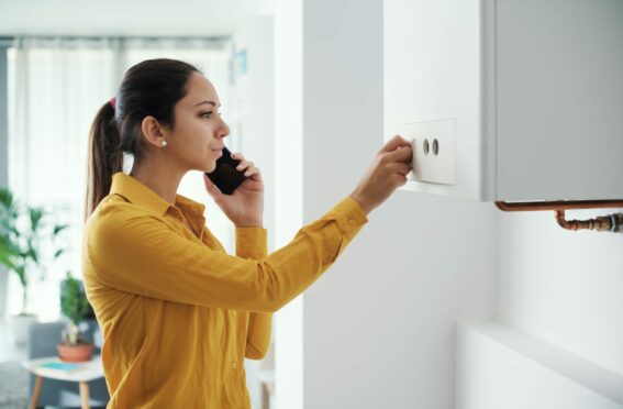 Worried woman calling a boiler breakdown emergency service using her smartphone